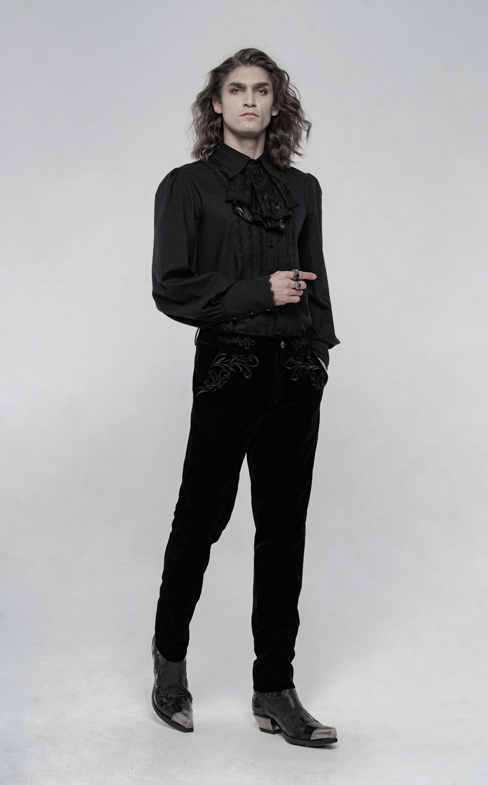 Victorian style model wearing black velvet gothic trousers with intricate embroidery and ruffled shirt, embodying gothic elegance.