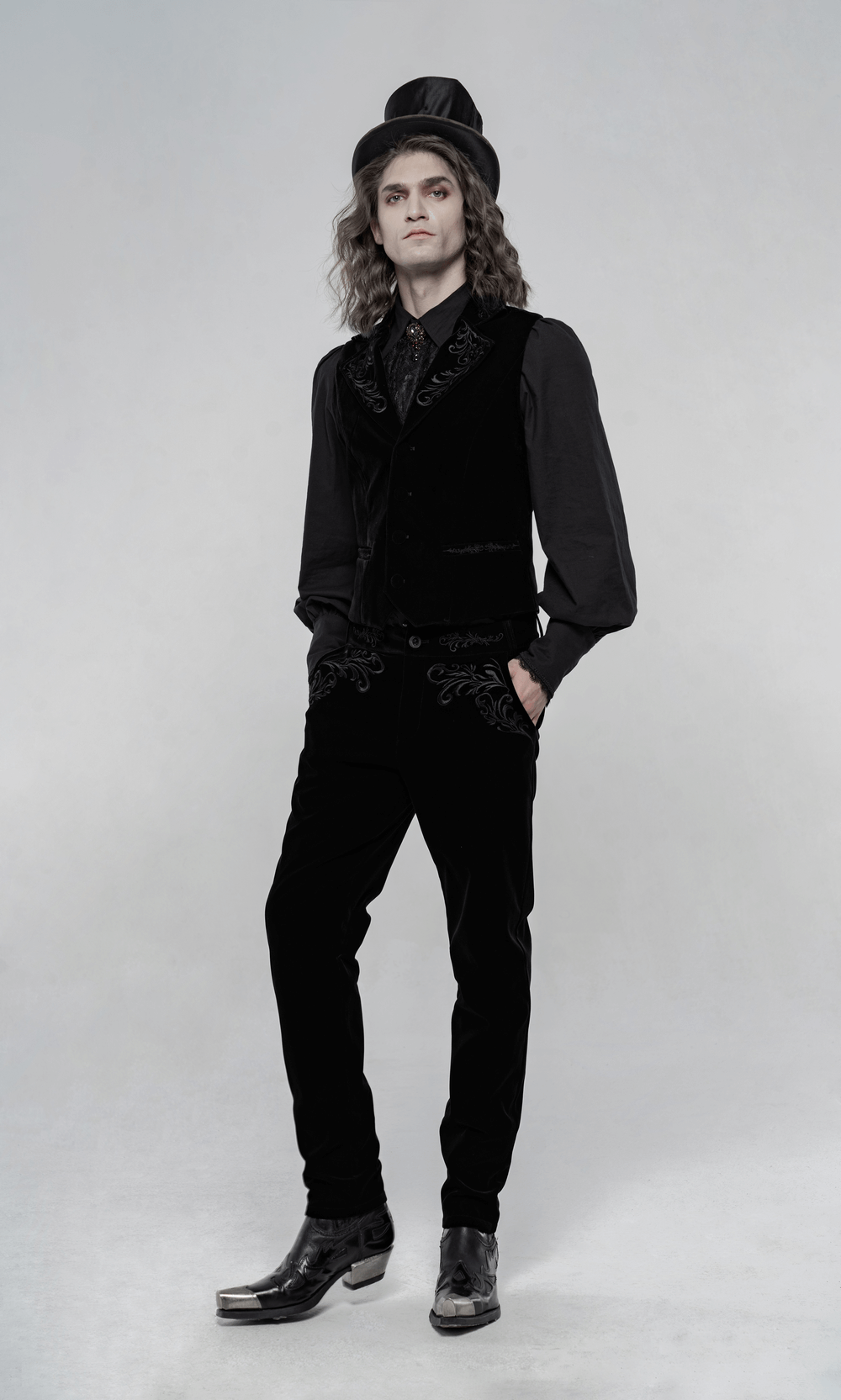 Victorian style model wearing black velvet Gothic trousers with intricate embroidery and a stylish top hat.