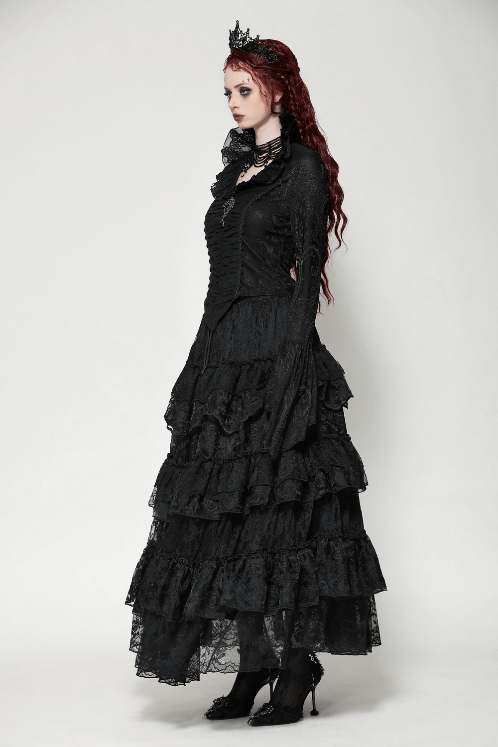 Elegant gothic model in black Victorian dress with ruffled layers and long sleeves, showcasing timeless sophistication and style.