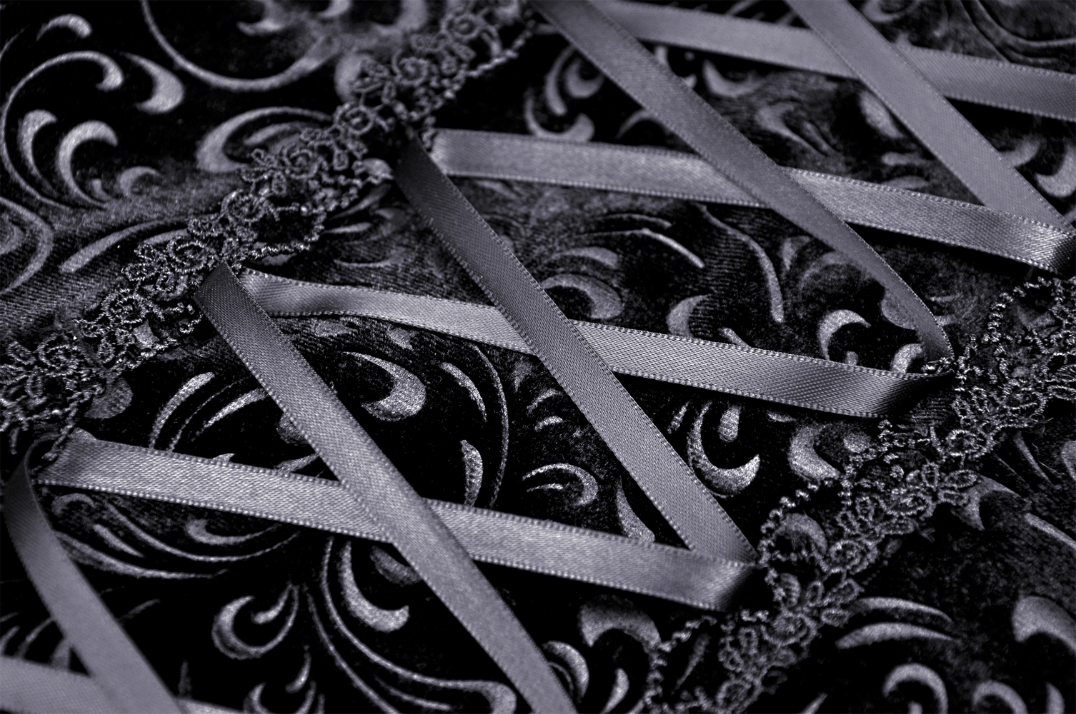 Close-up of black velvet fabric with intricate baroque patterns and lace trim, perfect for Gothic Victorian fashion.