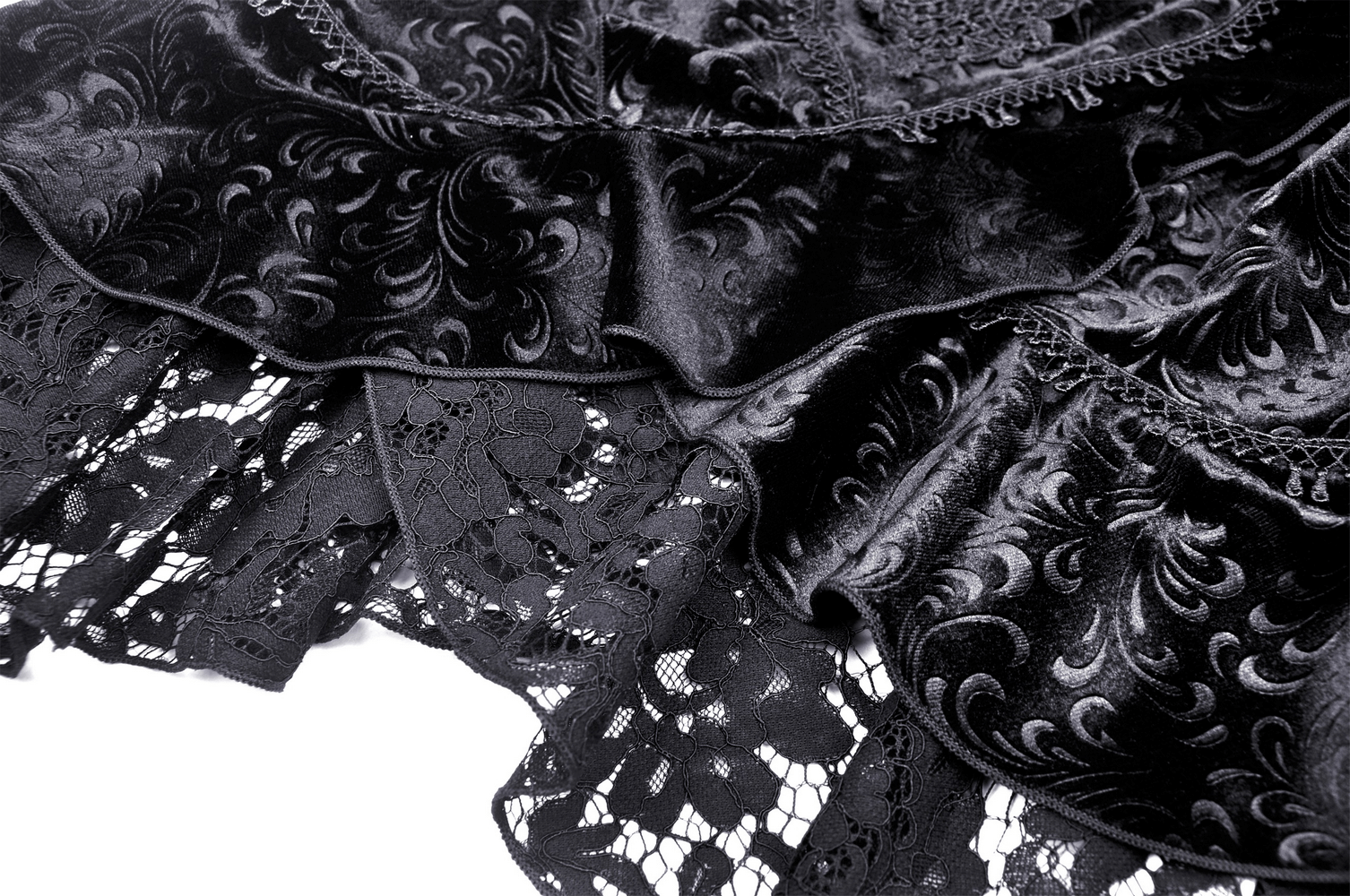 Close-up of black velvet fishtail skirt with intricate lace overlay and baroque patterns, highlighting gothic elegance.