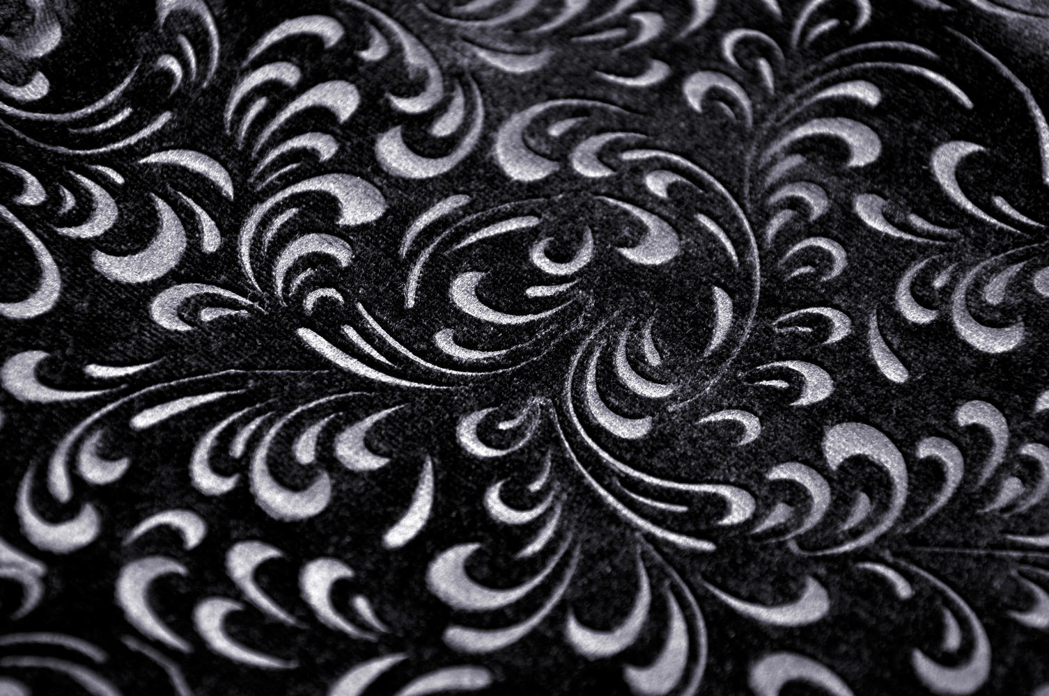 Close-up of luxurious black velvet fabric with intricate baroque patterns, perfect for gothic Victorian apparel.