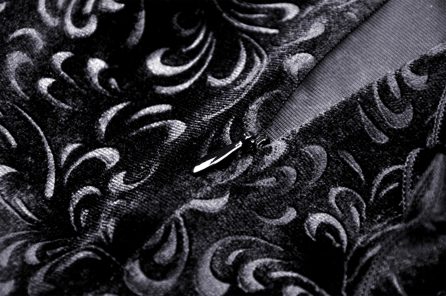 Close-up of black velvet fabric with intricate baroque patterns and zipper detail for Victorian skirt.