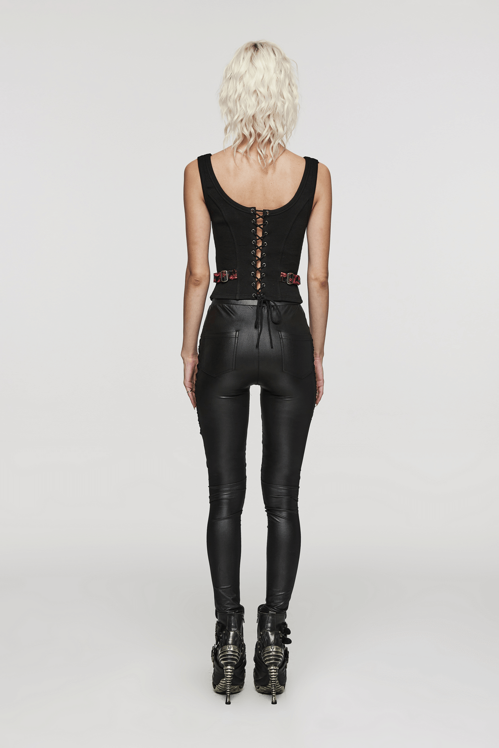 Back view of a woman in a black steampunk waistcoat and fitted pants, showcasing intricate lace-up details.