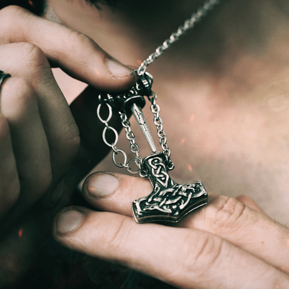 Viking Thor's Hammer Necklace with Celtic Knotwork worn by a person revealing a hidden dagger inside.