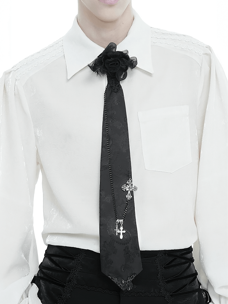 Vintage black necktie with cross pendant and rose, showcasing gothic style on a white shirt.