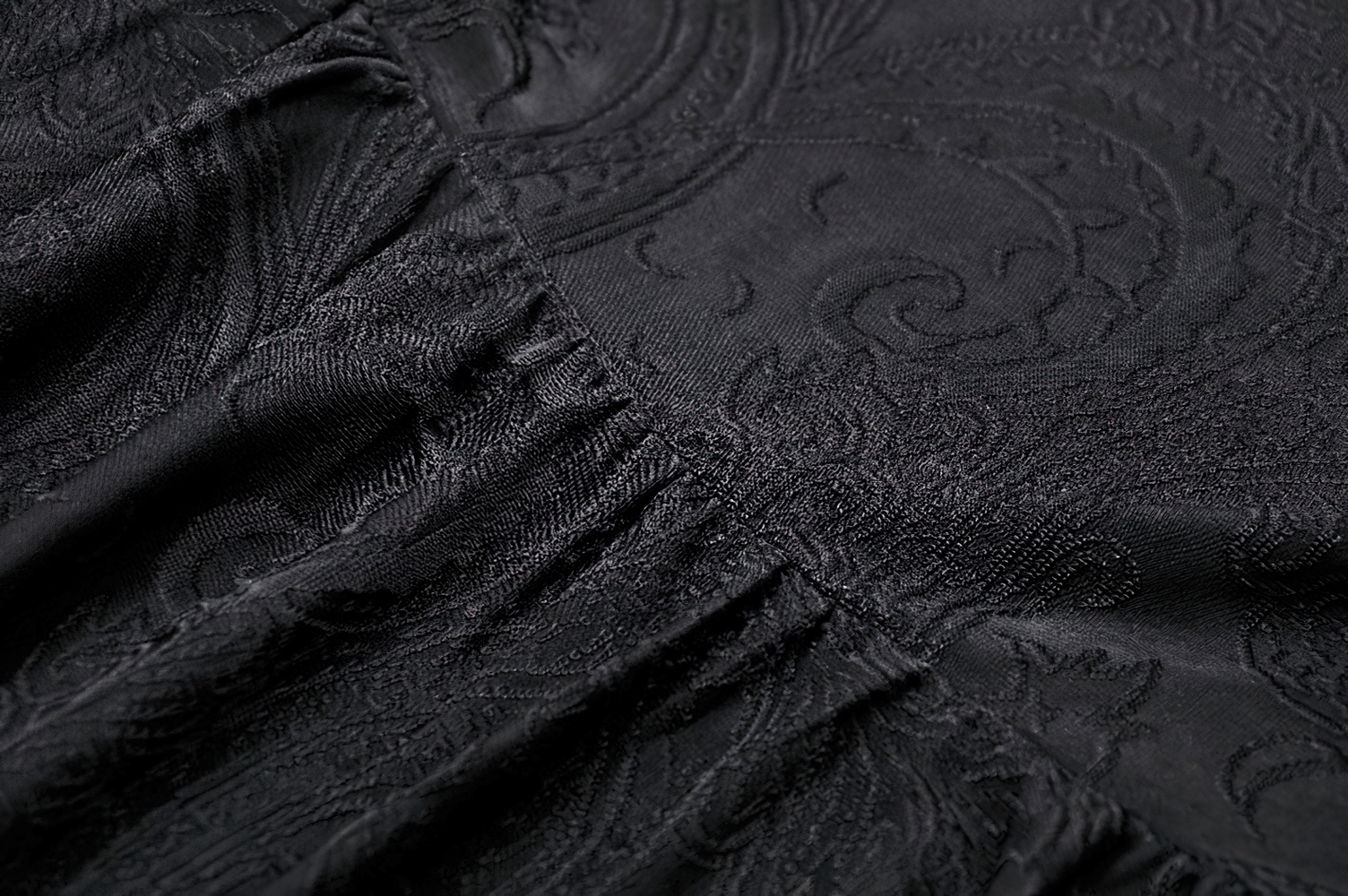 Close-up of intricate black fabric with elegant paisley patterns, perfect for a vintage gothic dress.