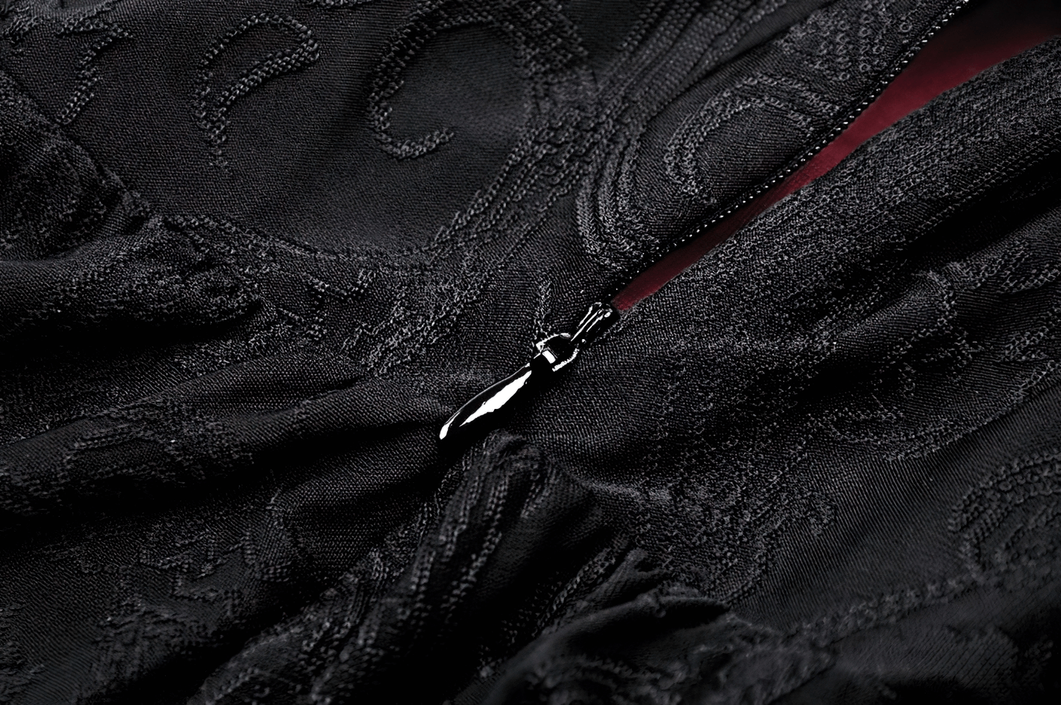 Close-up of velvet fabric with intricate patterns and a silver zipper, showcasing gothic elegance.