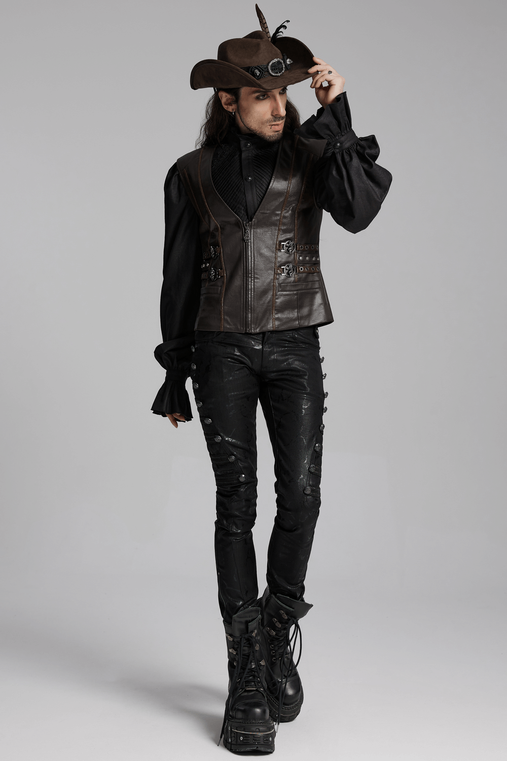 Stylish man in dark cowboy hat with feathers and fringe, wearing gothic leather vest and boots, embodying punk inspiration.
