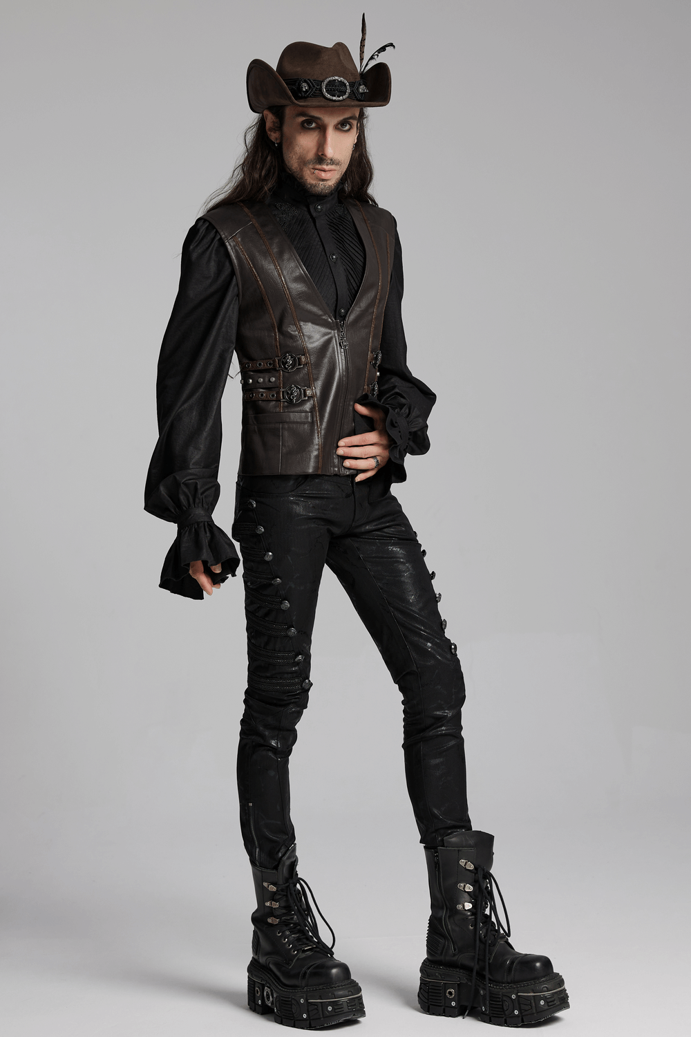 Man wearing vintage dark cowboy hat with feathers, gothic leather outfit, and punk-inspired knee-high boots.