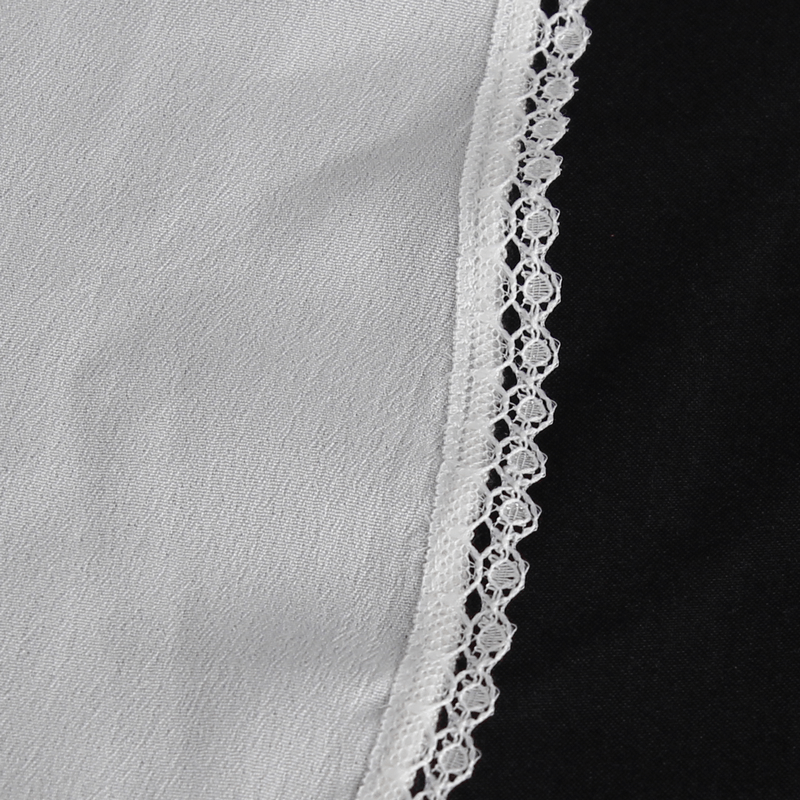 Close-up of a white fabric shirt featuring delicate lace trim and a contrasting black background.