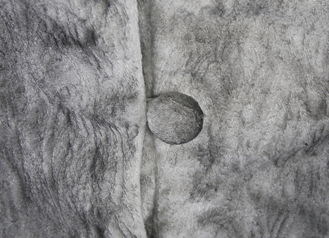 Close-up of textured fabric with a button, showcasing intricate details and a vintage feel.