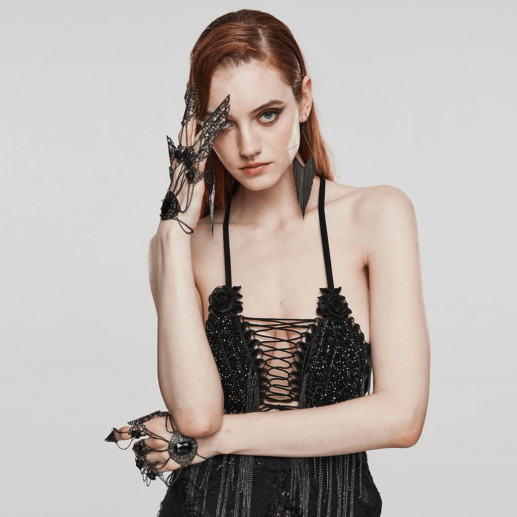 Gothic finger bracelet with tassels and rose buckle, worn by model in dramatic black outfit.