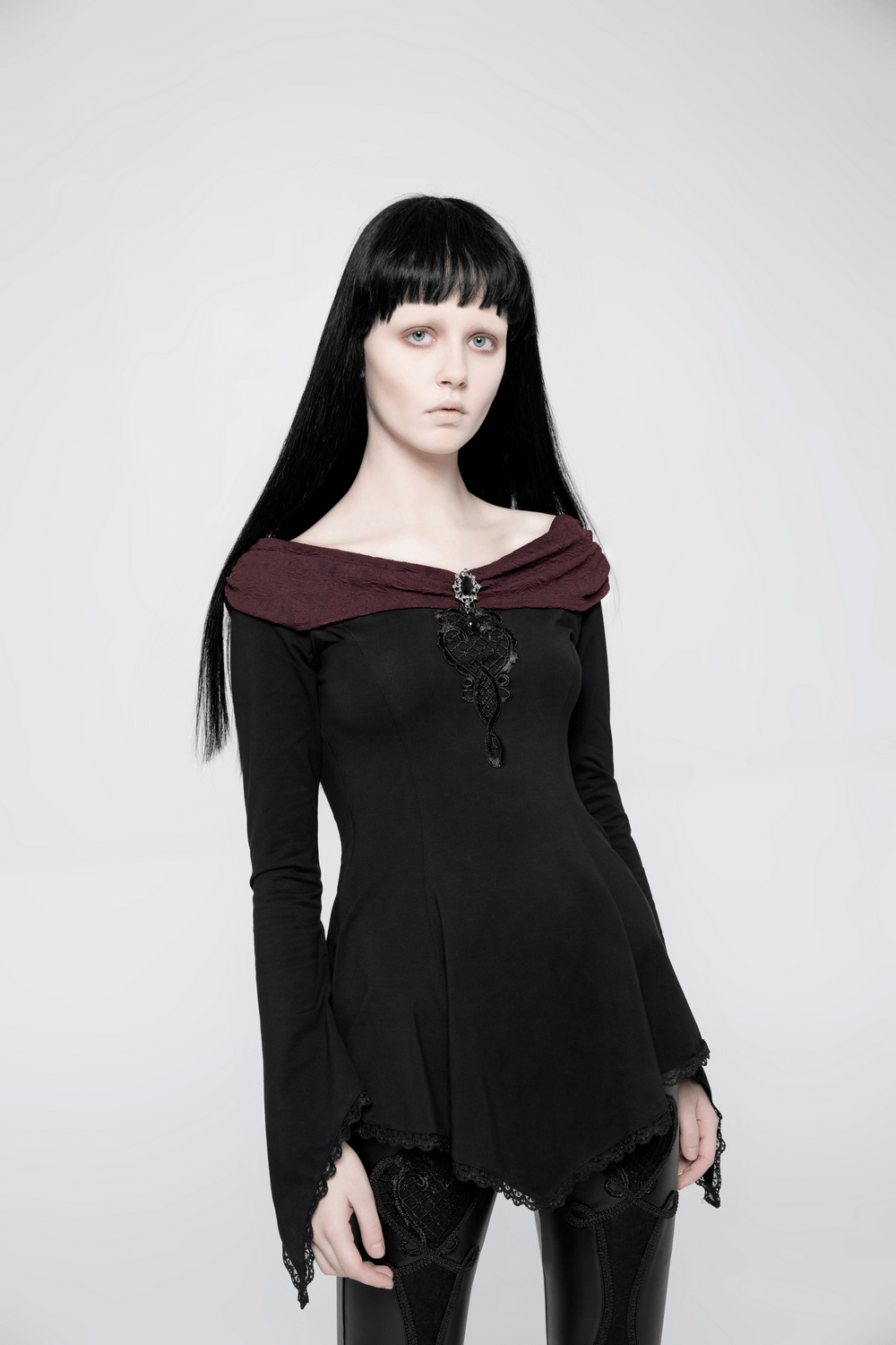 Vintage Gothic long sleeve top with lace trim and brooch, modeled by a person with long black hair.
