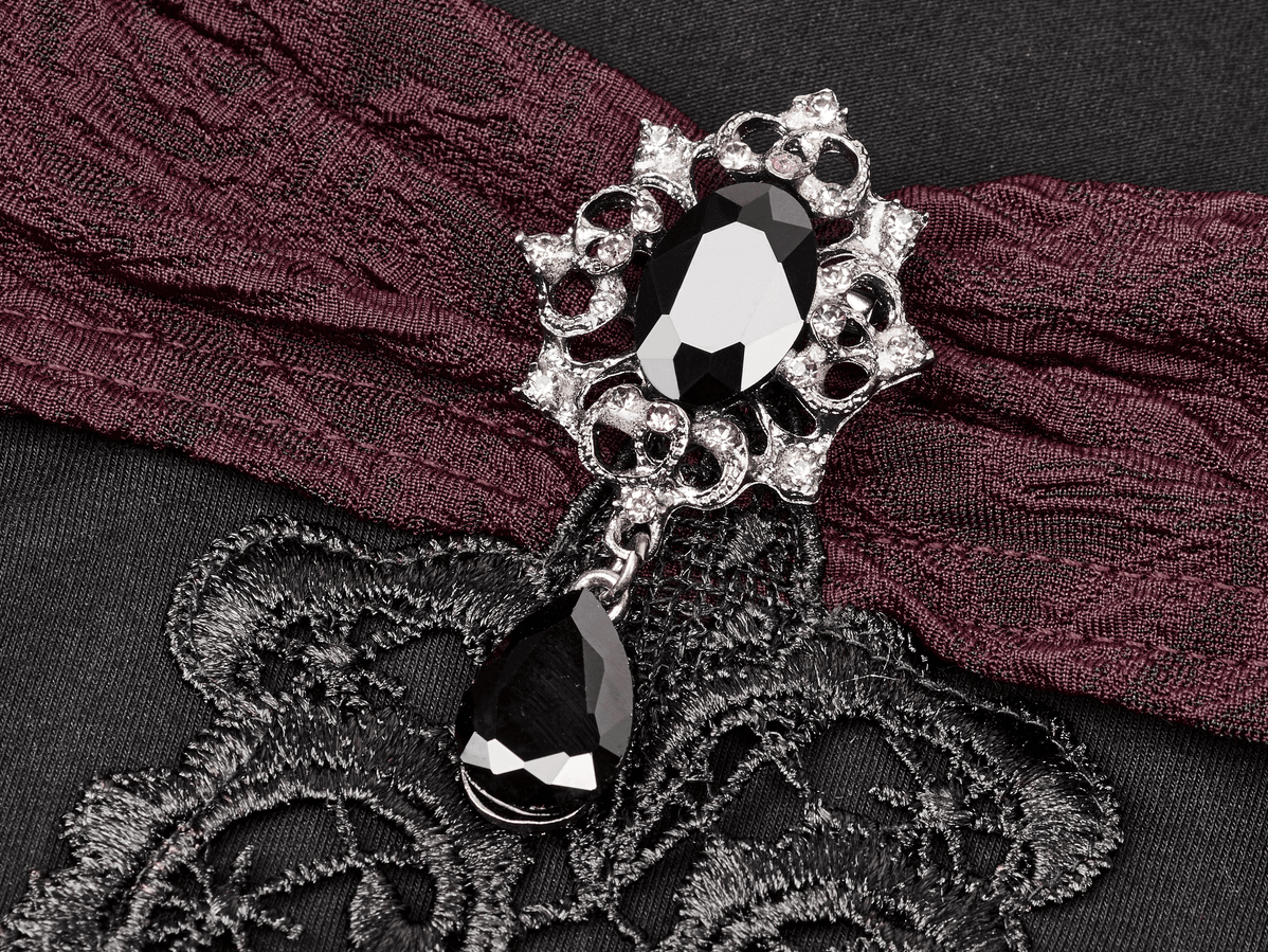 Close-up of a Gothic brooch featuring black jewels and lace trim on a vintage top.