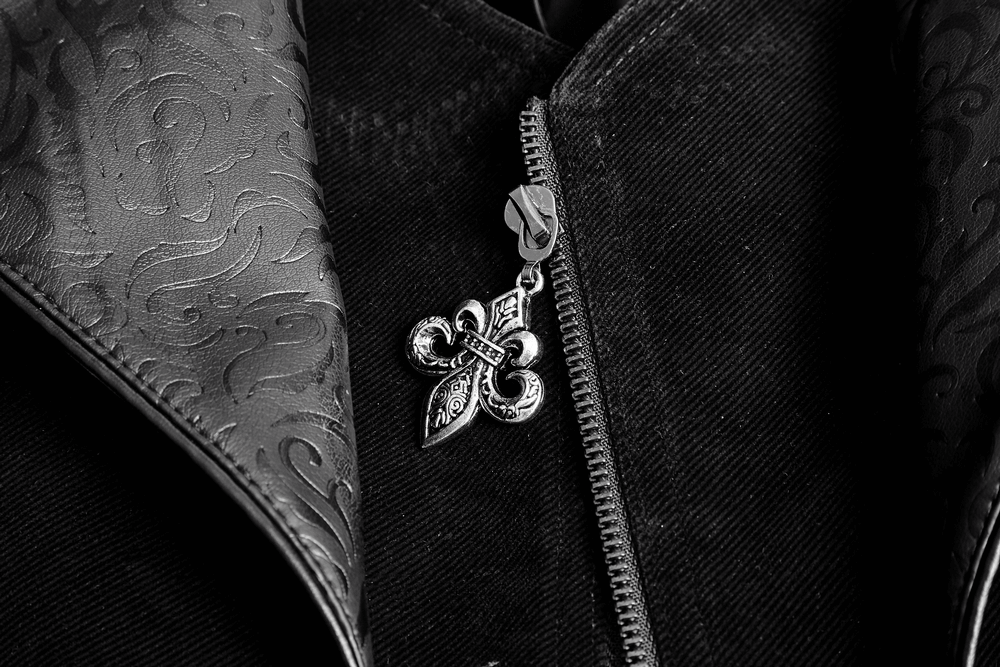 Close-up of a vintage gothic cloak zipper featuring an ornate silver fleur-de-lis charm on a velvet and leather fabric.