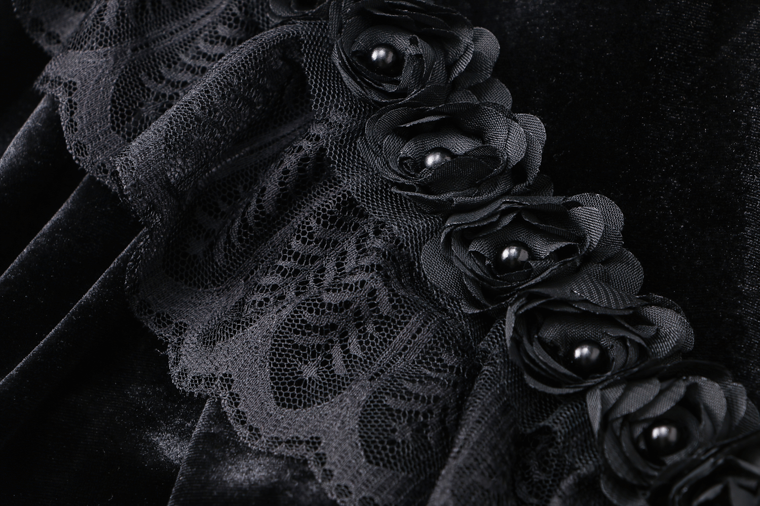 Close-up of a vintage gothic velvet capelet showcasing black lace trim and pearl-embellished flowers for dark elegance.