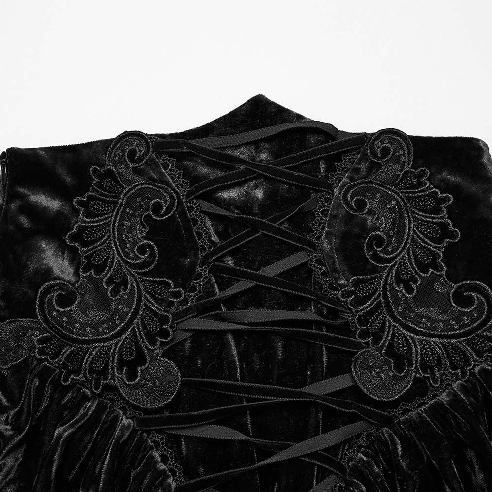 Close-up of vintage gothic velvet fabric with intricate lace and pleated details in black.