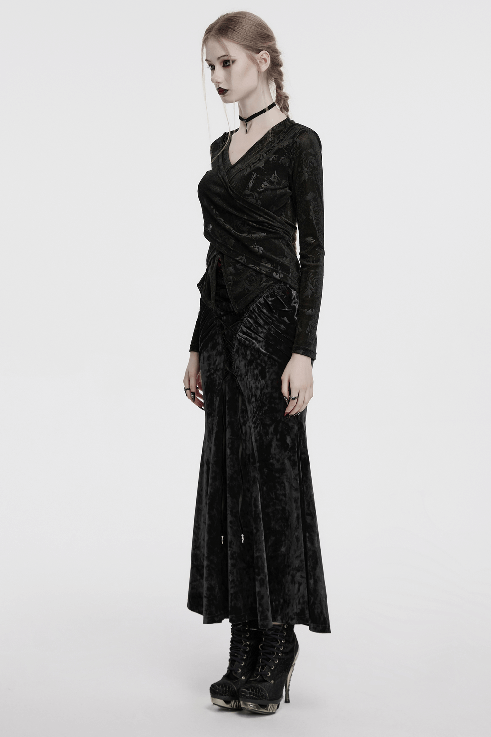 Woman in vintage gothic velvet skirt with lace details, side view, showcasing elegant pleats and high waist design.