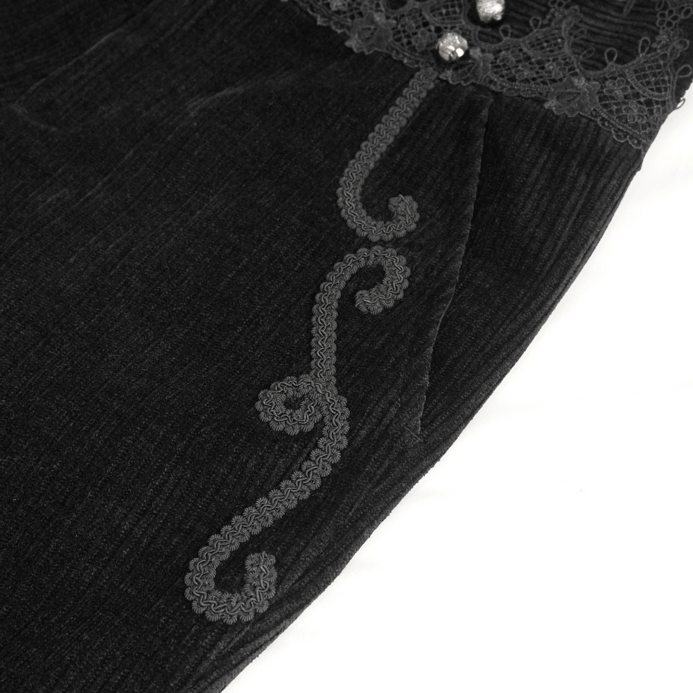 Close-up of black corduroy pants with lace trim and decorative embroidery detail