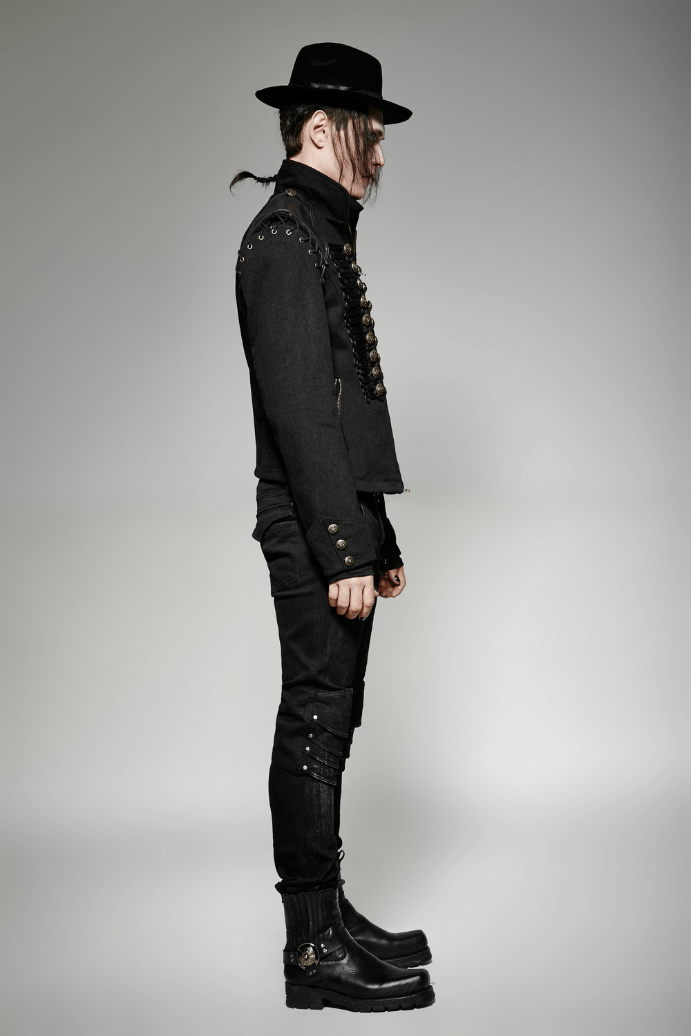 Side view of a model wearing a vintage-inspired military jacket with a stylish hat and edgy boots.