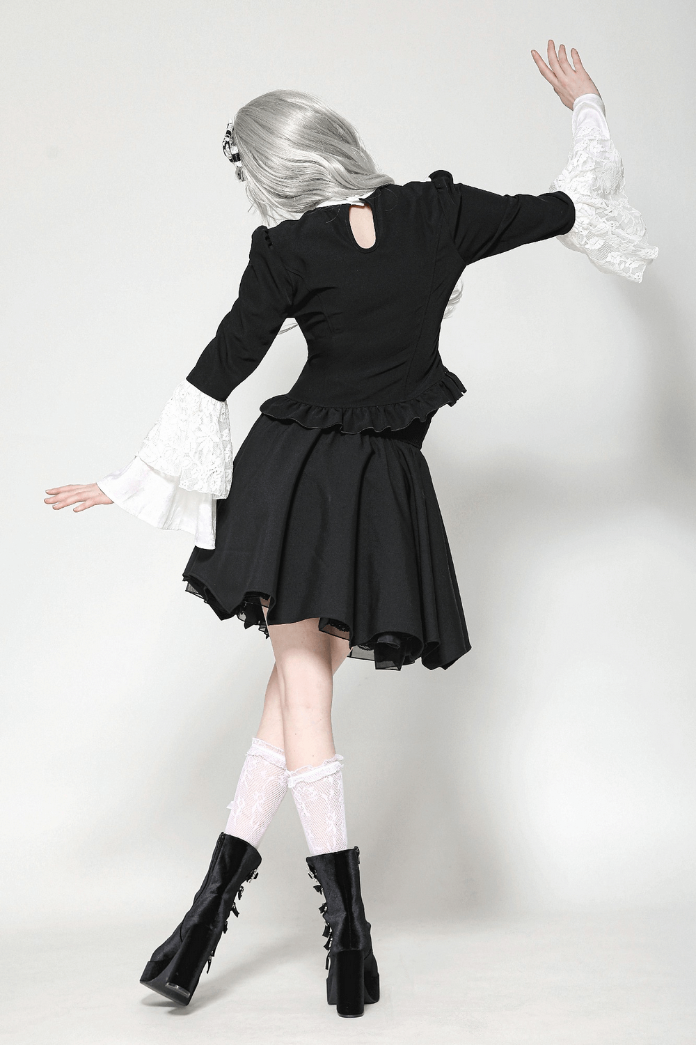 Back view of a woman in a vintage black peplum blouse with white lace bell sleeves and flared skirt.