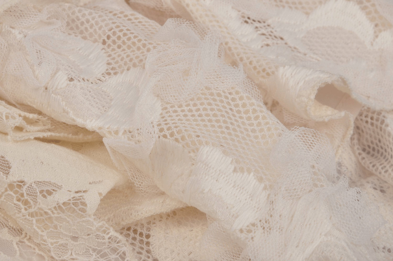Close-up of vintage ivory lace fabric showcasing intricate floral patterns and delicate textures.