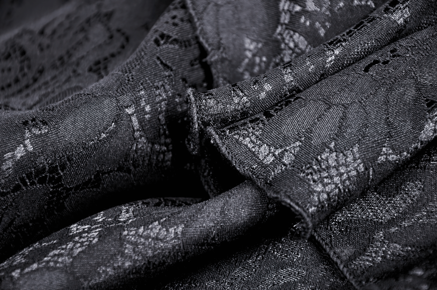 Close-up of intricate black lace fabric, showcasing elegant patterns and textures for vintage or gothic styles.