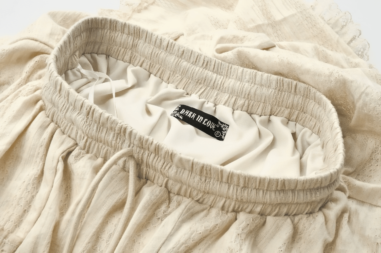 Close-up of the elastic waistband and label of a vintage cream boho skirt with lace trim.