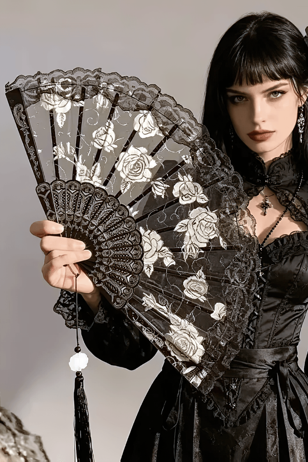 Vintage Rose Lace Folding Fan with Tassel Pendant held by a model in a gothic outfit, showcasing intricate lace and floral design.