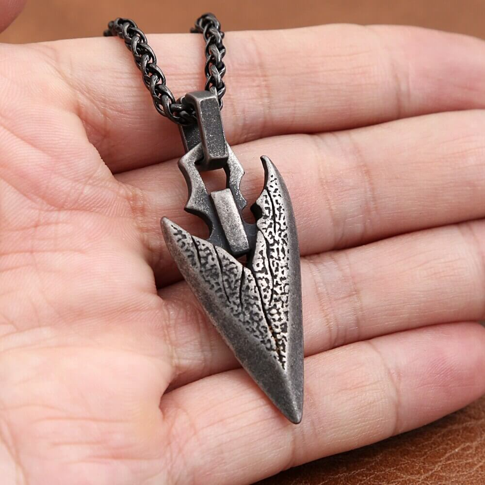 Vintage stainless steel arrowhead pendant necklace held in hand, showcasing bold design and timeless style.