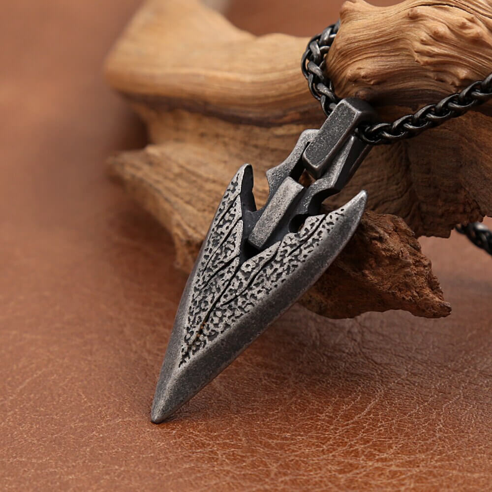 Vintage stainless steel arrowhead pendant necklace on a rustic background, symbolizing timeless fashion charm.