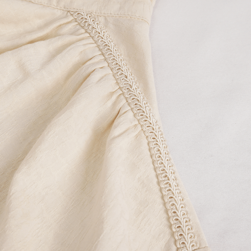 Close-up of vintage stand collar cotton shirt showing soft fabric and detailed embroidery on cream color.