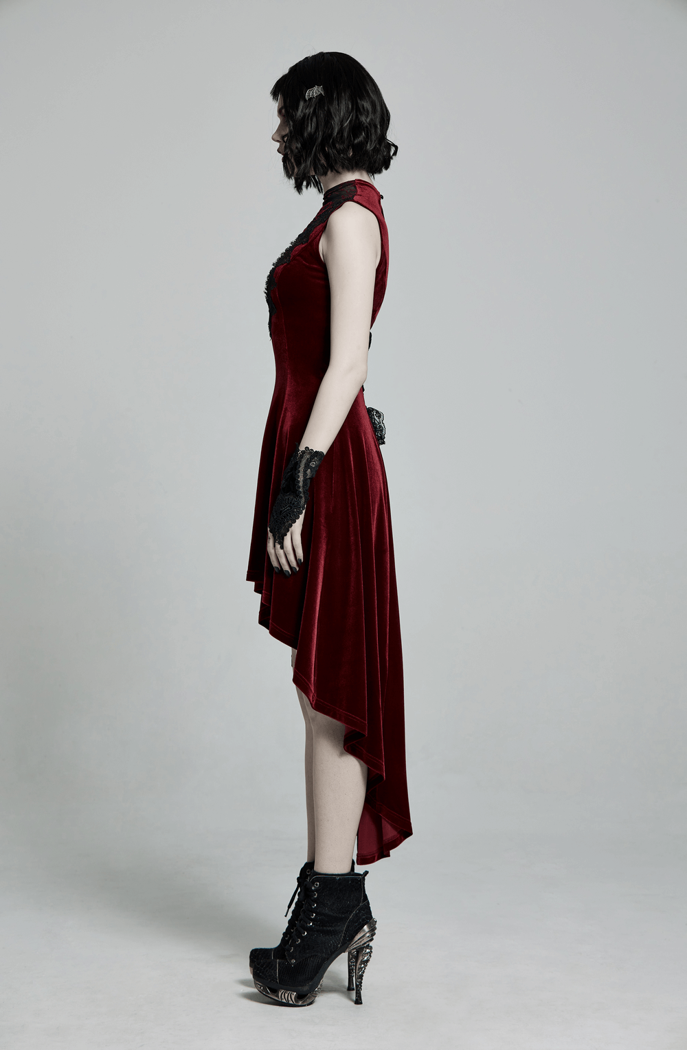 Side view of a vintage-inspired red velvet high-low dress showcasing lace detail and a gothic style.