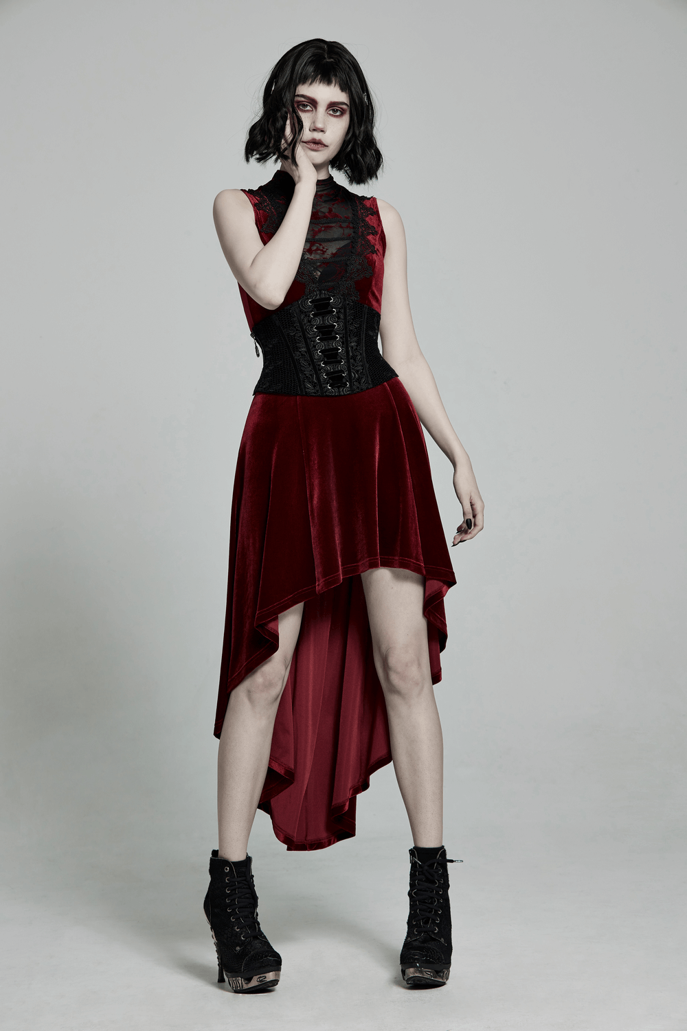 Gothic model wearing a vintage velvet cincher belt with a lace-up back and a stylish high-low red dress.