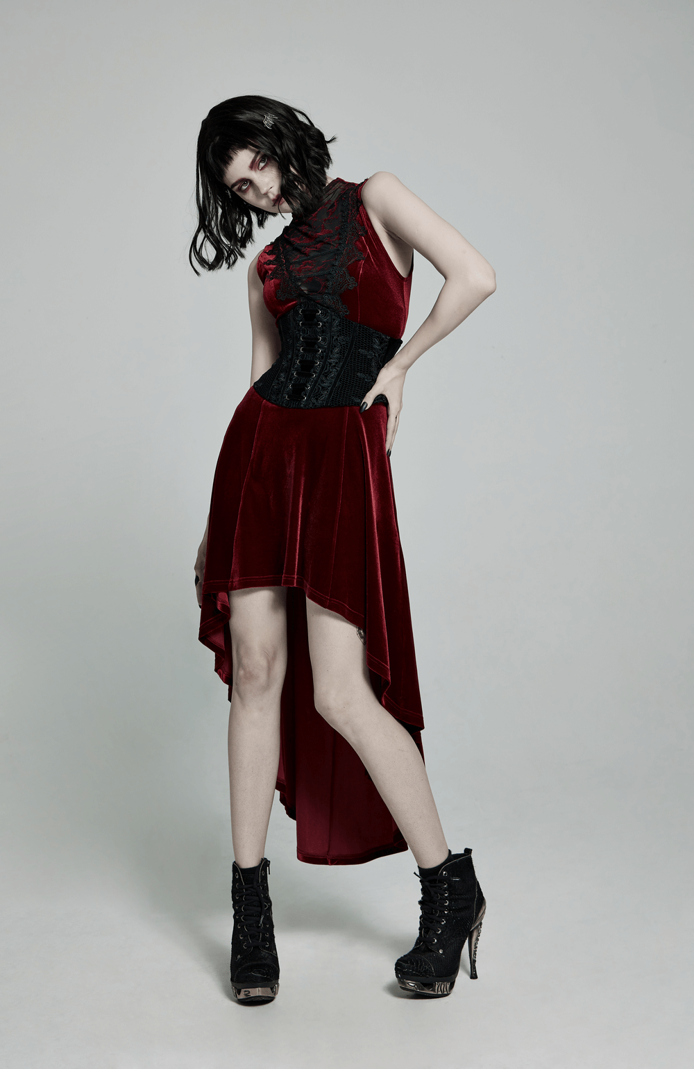 Model wearing a vintage velvet cincher with lace-up back, paired with a flowing red dress and stylish black heels.