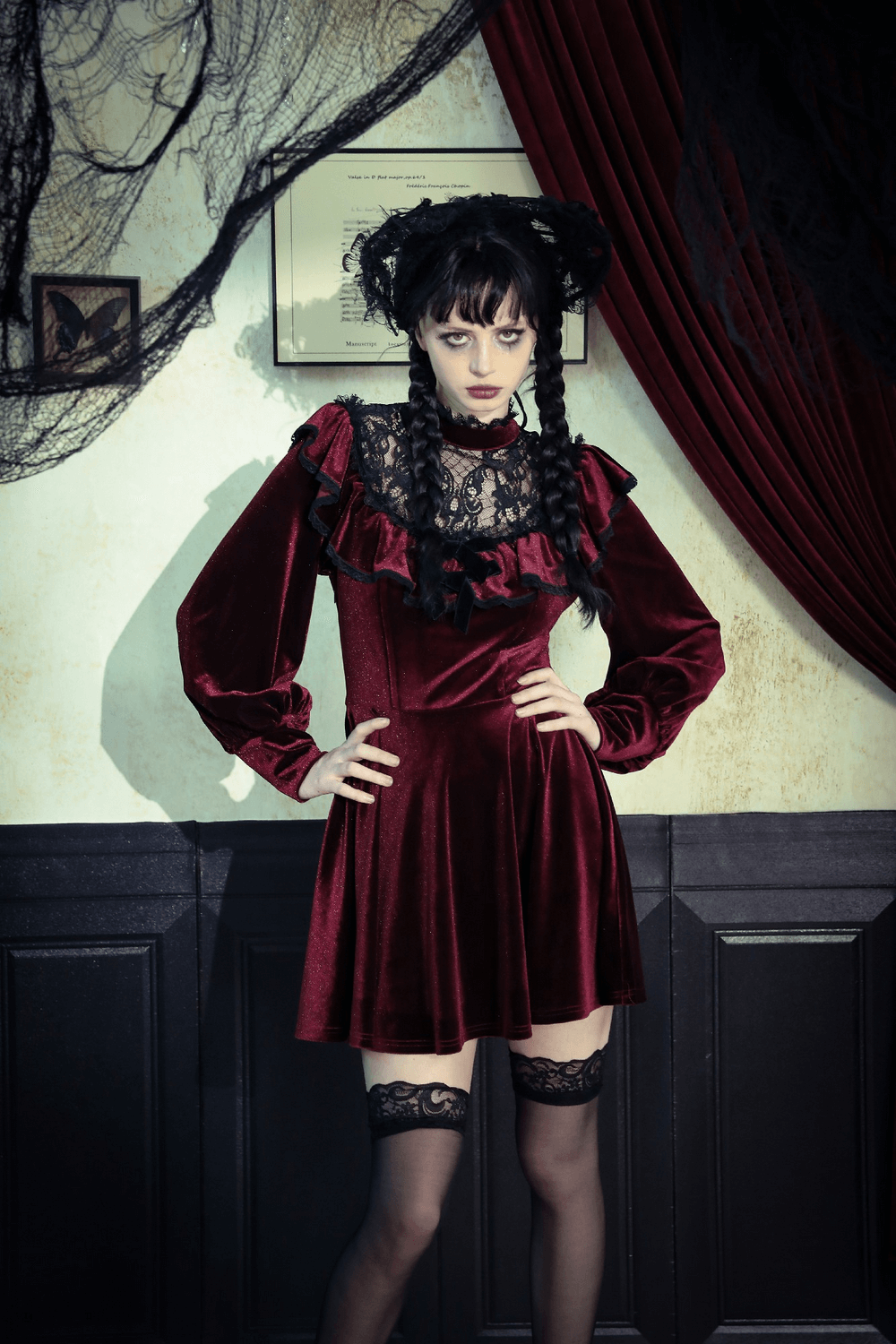 Gothic vintage velvet dress with black lace, ruffles, and puff sleeves, worn by a woman standing in a moody, elegant setting.