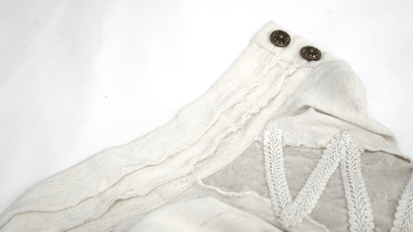 Detail of vintage white shirt with buttons and ruffles, showcasing gothic style elegance.
