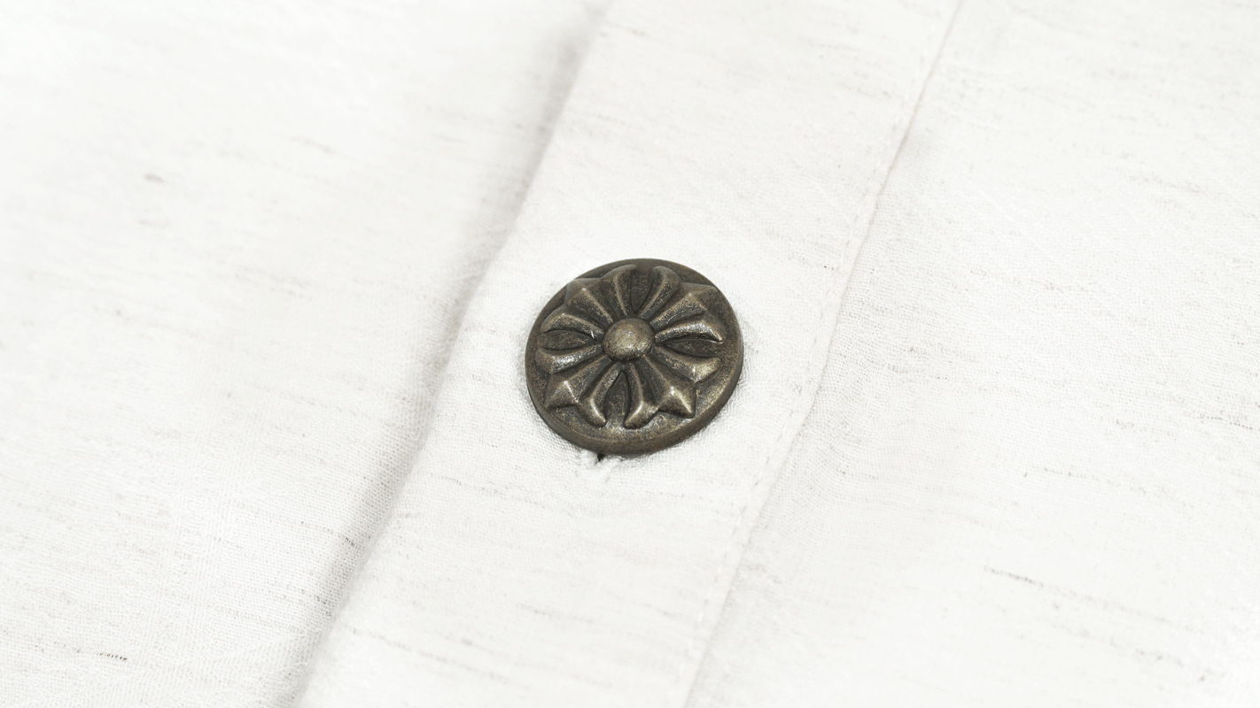 Close-up of a vintage white shirt button with floral design, perfect for gothic style fashion.