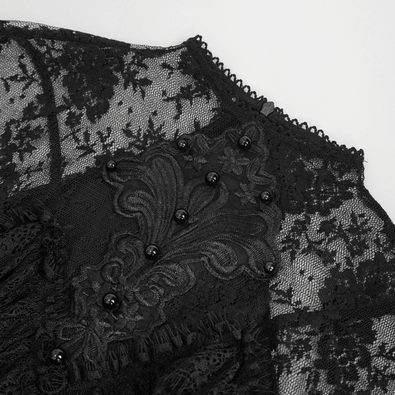 Close-up of black lace detailing on vintage women's dress with elegant beading and intricate design.