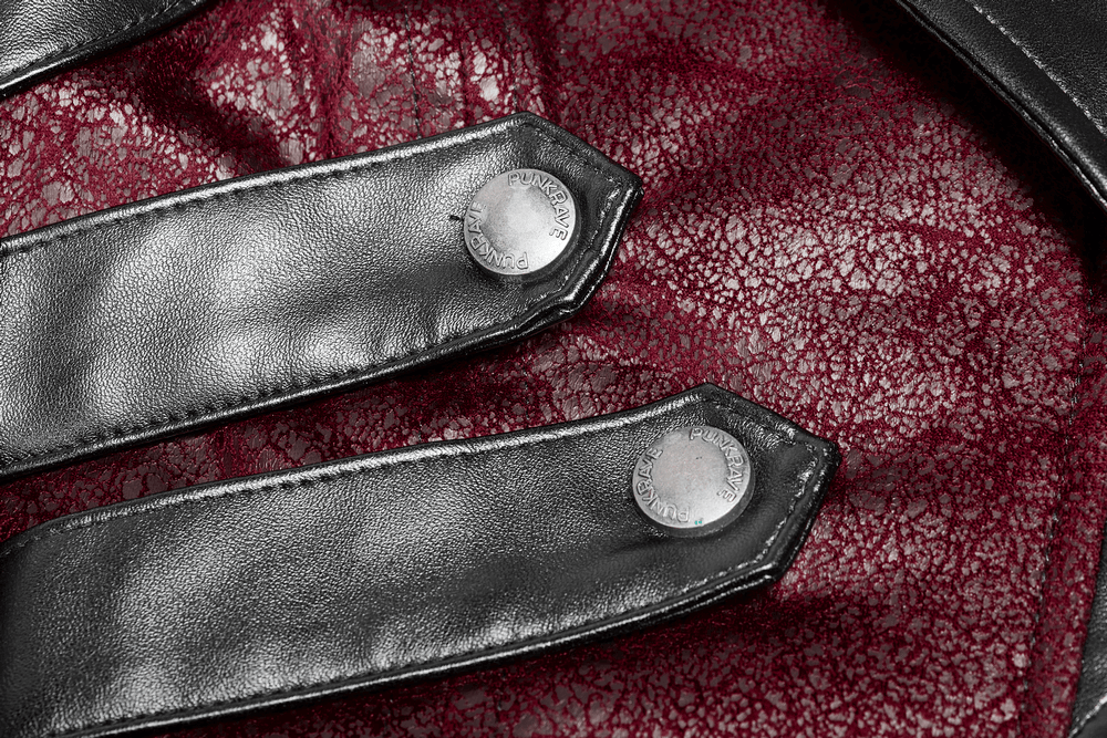 Close-up of adjustable black leather straps and buttons on a vintage red punk jacket.