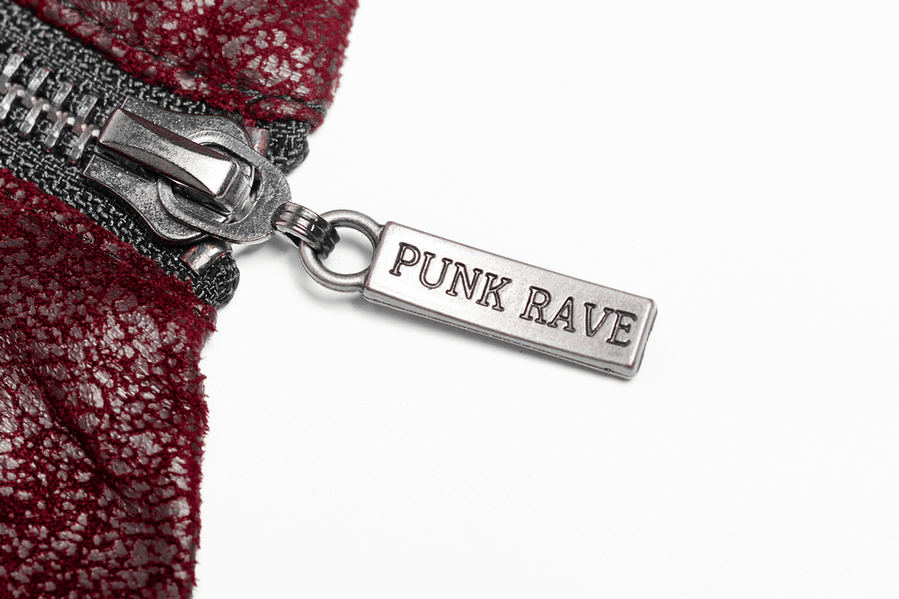 Close-up of a vintage red leather jacket zipper pull with 'PUNK RAVE' tag, showcasing punk style and attention to detail.
