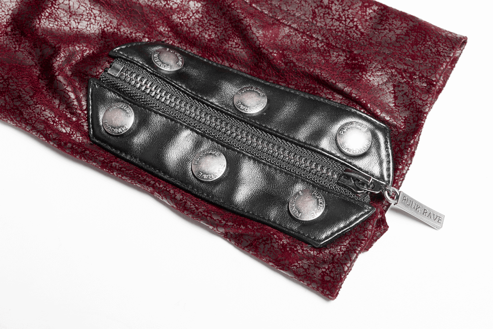 Close-up of vintage red leather jacket strap with zipper and metallic buttons, showcasing punk style and texture contrast.