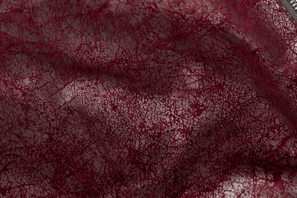 Close-up of textured vintage red leather fabric with a crackled pattern for a punk aesthetic.