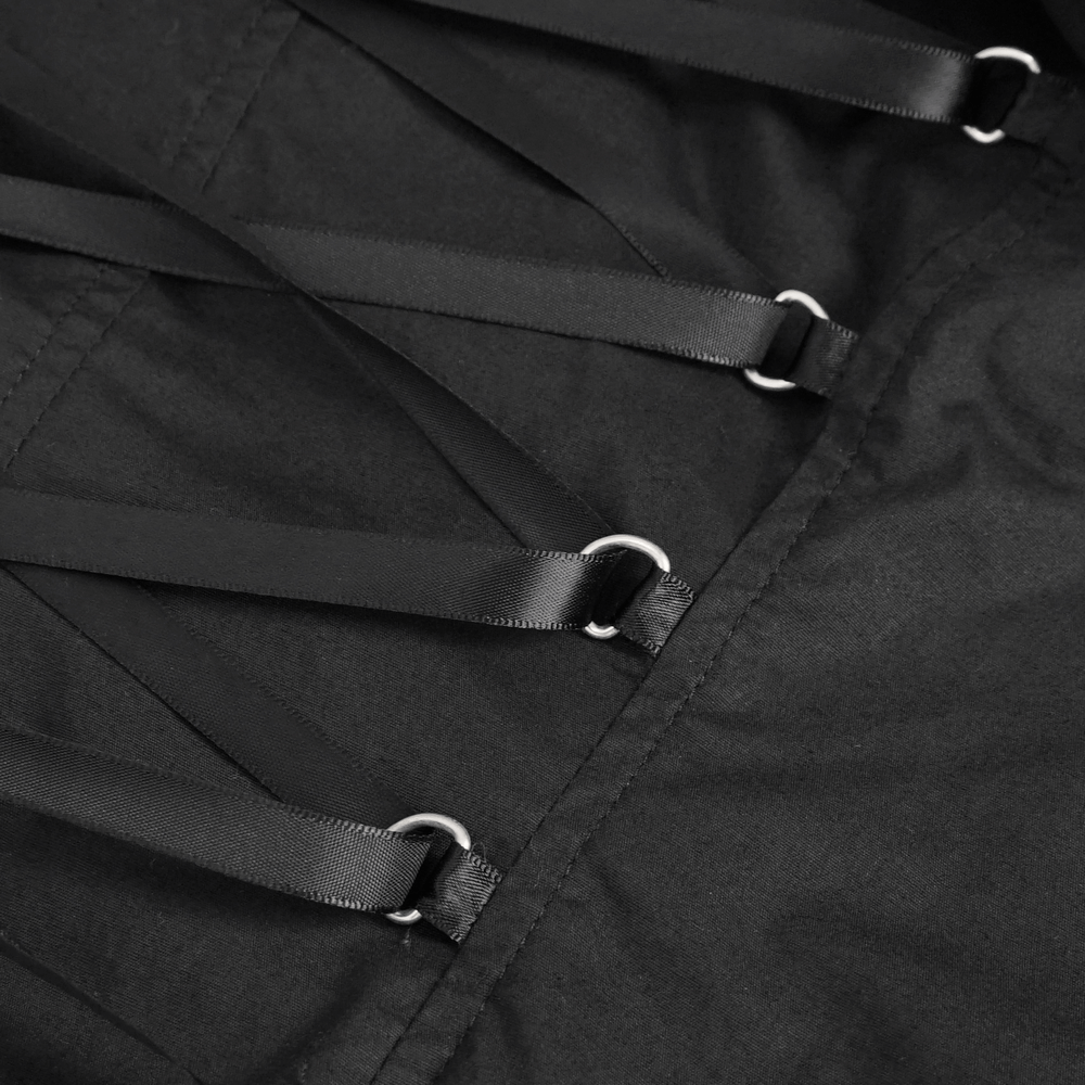 Close-up of black vintage blouse detailing with satin straps and metal rings, showcasing gothic elegance.