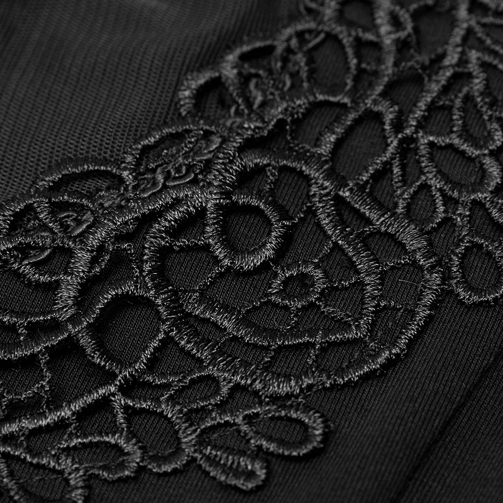 Close-up of delicate black floral embroidery on soft knit fabric for a stylish off-shoulder t-shirt.