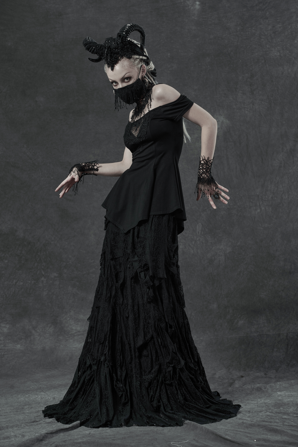 Model showcasing a stylish off-shoulder black top with intricate details and a dramatic black skirt.