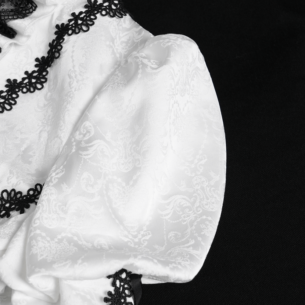 Close-up of the white gothic Victorian blouse with black lace trim and flared sleeves on a black background.
