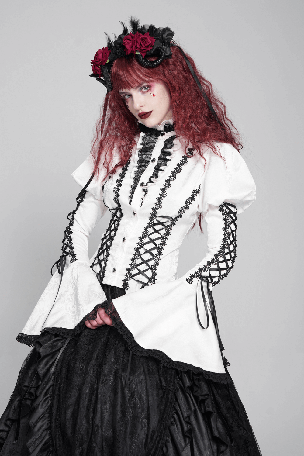 Model wearing a white gothic lace Victorian blouse with corset ties and flared sleeves, styled for a dramatic look.