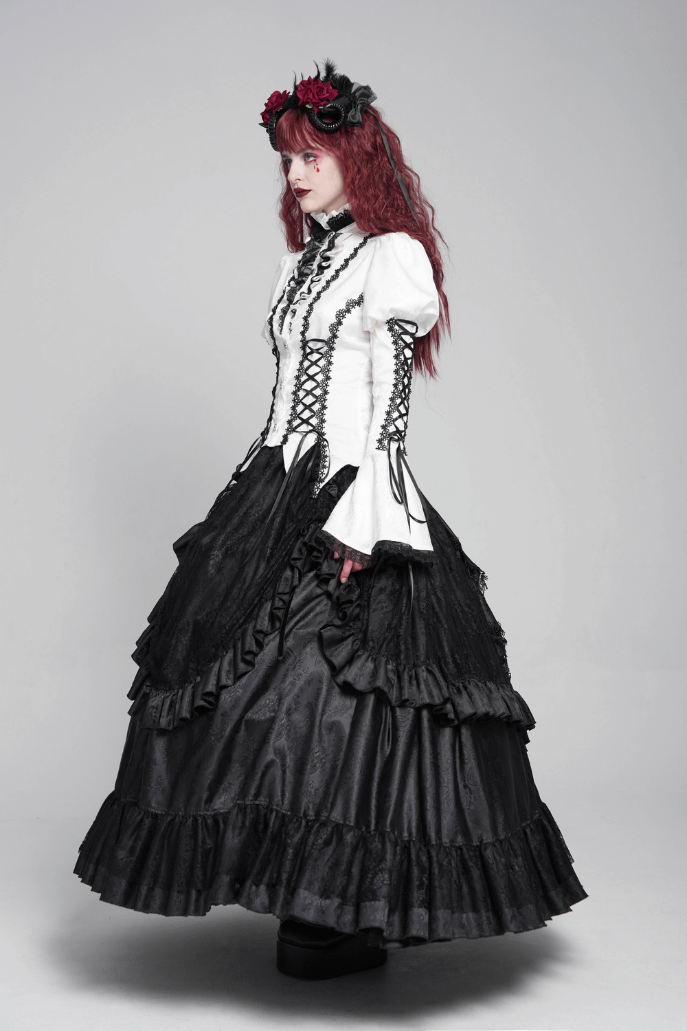 Elegant model in white gothic lace Victorian blouse and black ruffled skirt showcasing steampunk fashion.